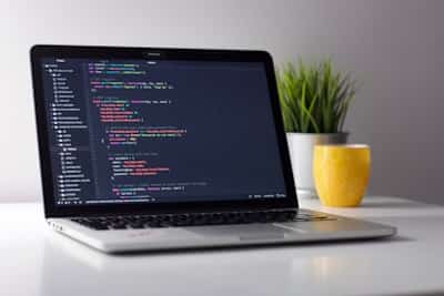 コードエディタが表示されたディスプレイで開発するエンジニア